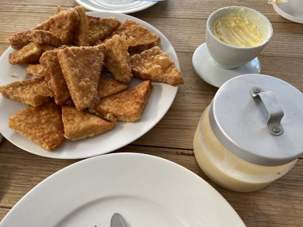 Photo of a plate full of HK-style french toast with a butter bell full of butter and a jar of condensed milk